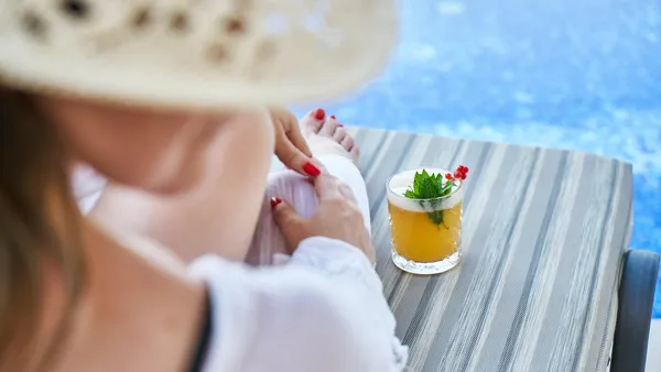 Piscina infinita de resort tropical com palmeiras ao fundo e céu azul