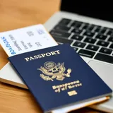 Passaporte e cartão de embarque sobre uma mesa, ao lado de um notebook, durante o planejamento de uma viagem à Europa