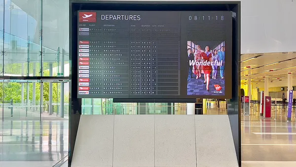 Painel de informações de voos em aeroporto internacional ilustrando emissão de passagens com milhas