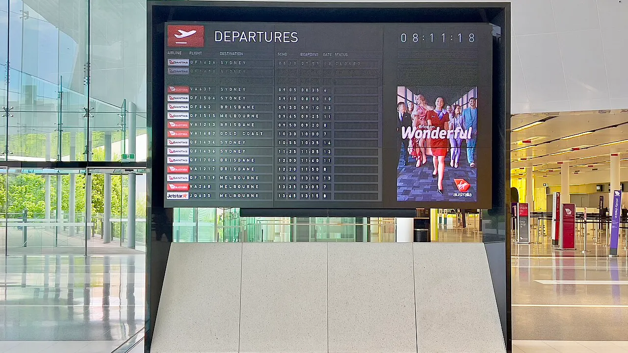 Painel de informações de voos em aeroporto internacional ilustrando emissão de passagens com milhas
