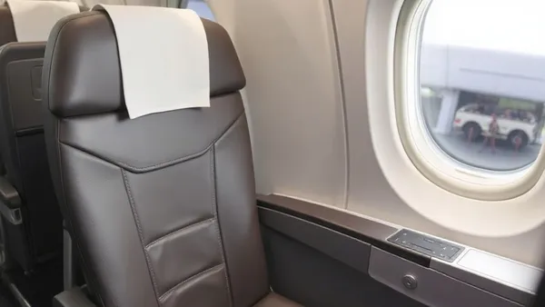 Poltrona executiva em avião internacional com iluminação suave e janela ao fundo