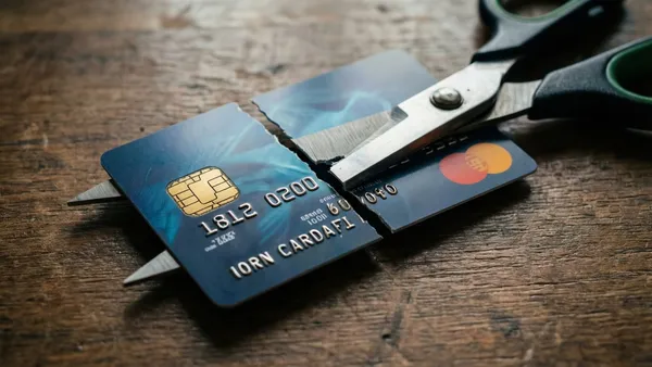 Cartão de crédito sendo cortado ao meio com tesoura, simbolizando cancelamento